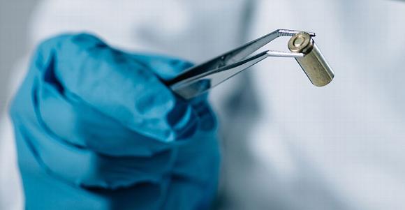 forensic expert looking at bullet casing